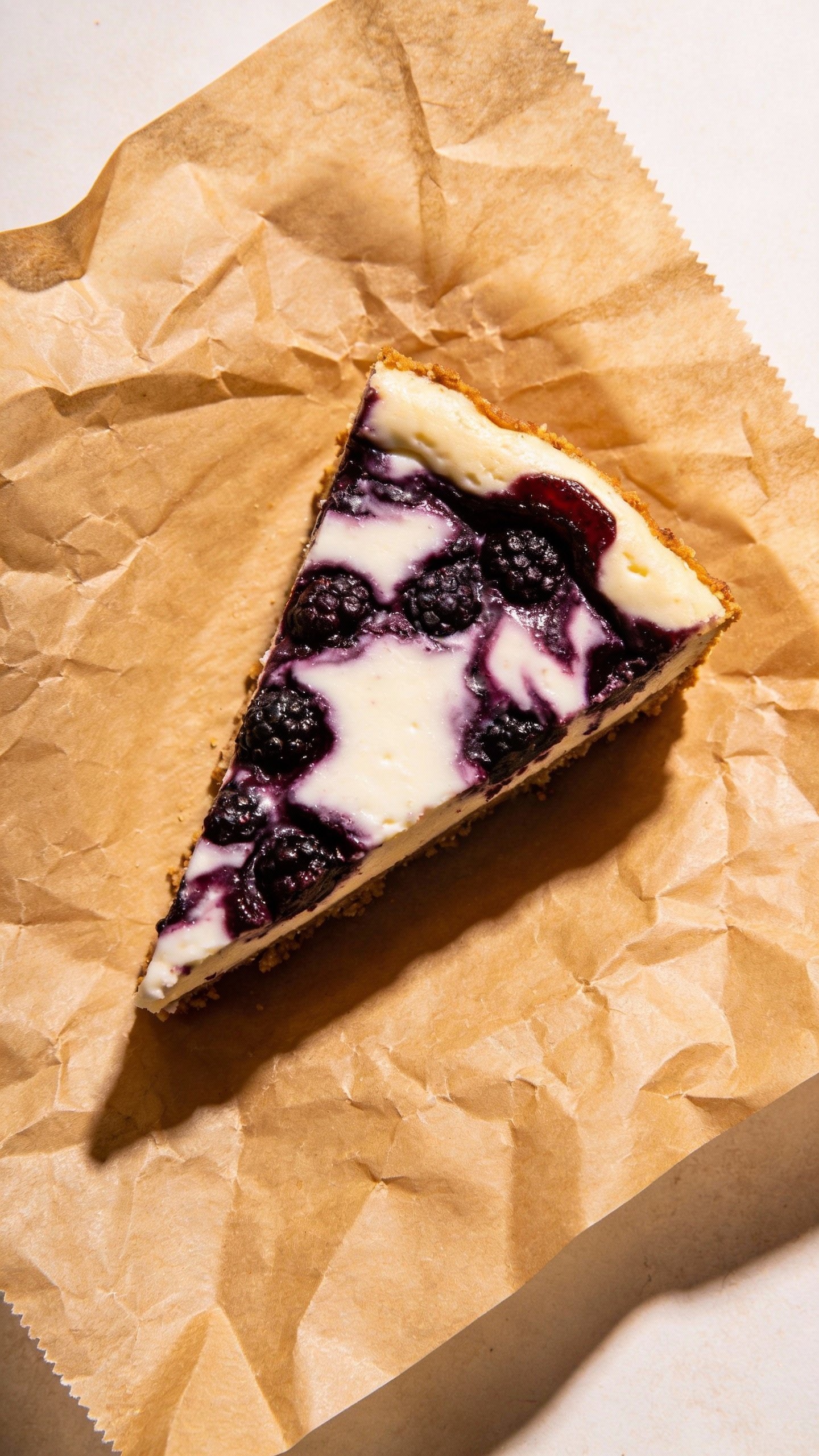 Overhead slice of blackberry-swirled keto cheesecake bar, parchment