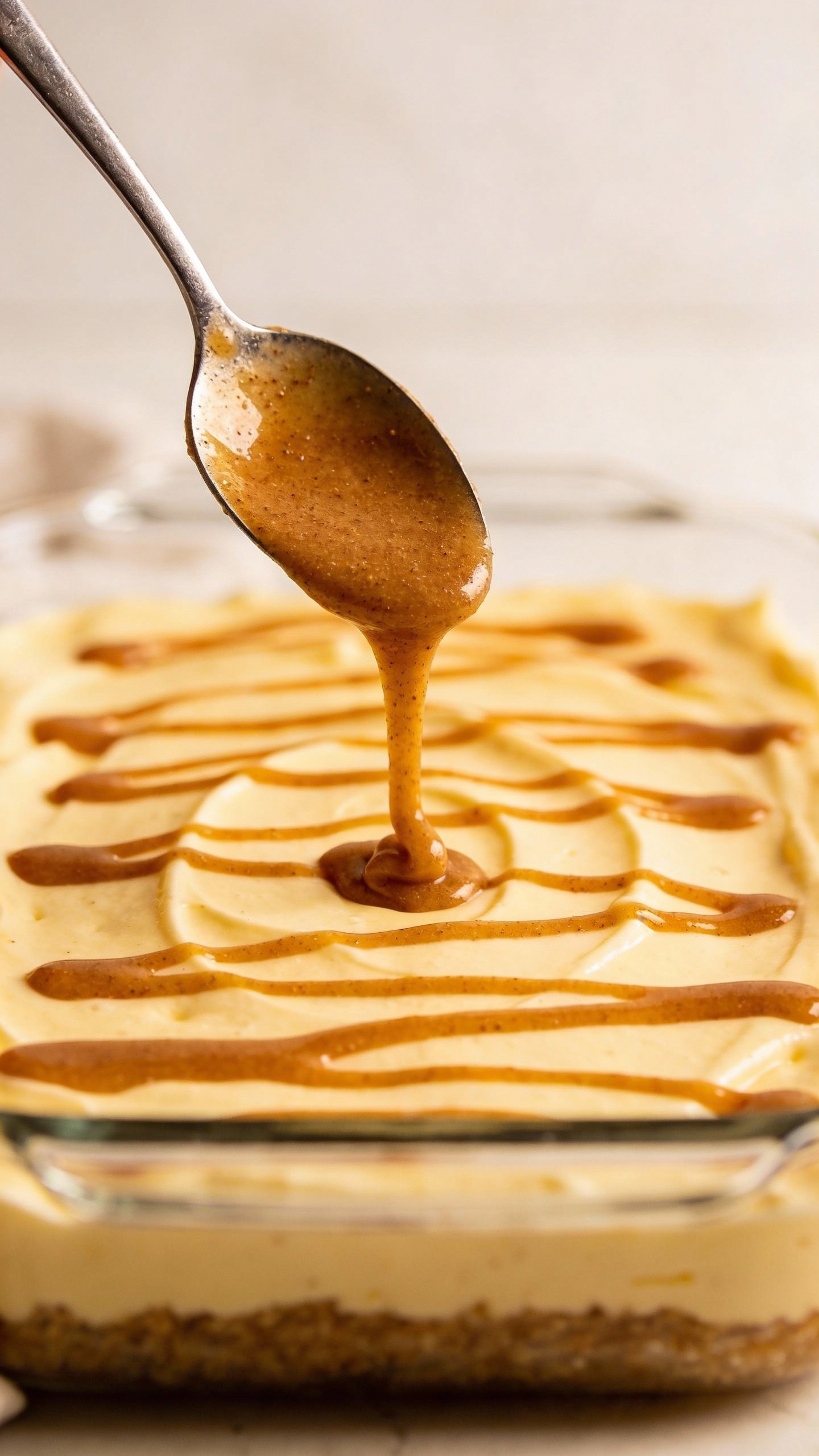spoon drizzling cinnamon butter swirl over cheesecake batter