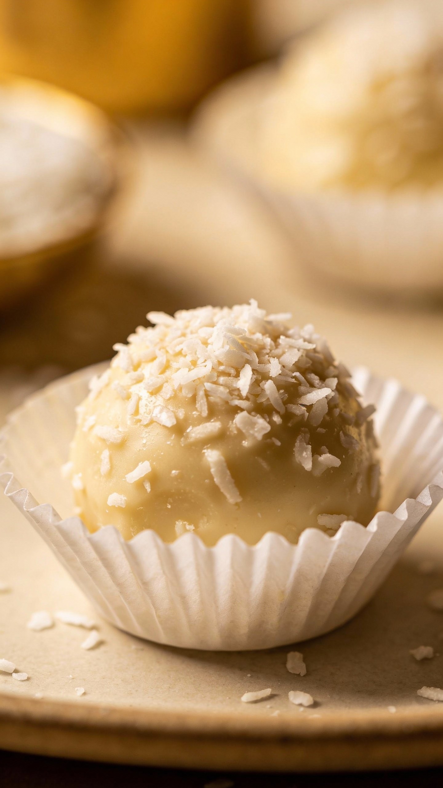 single keto fat bomb in white paper cup, sprinkled coconut