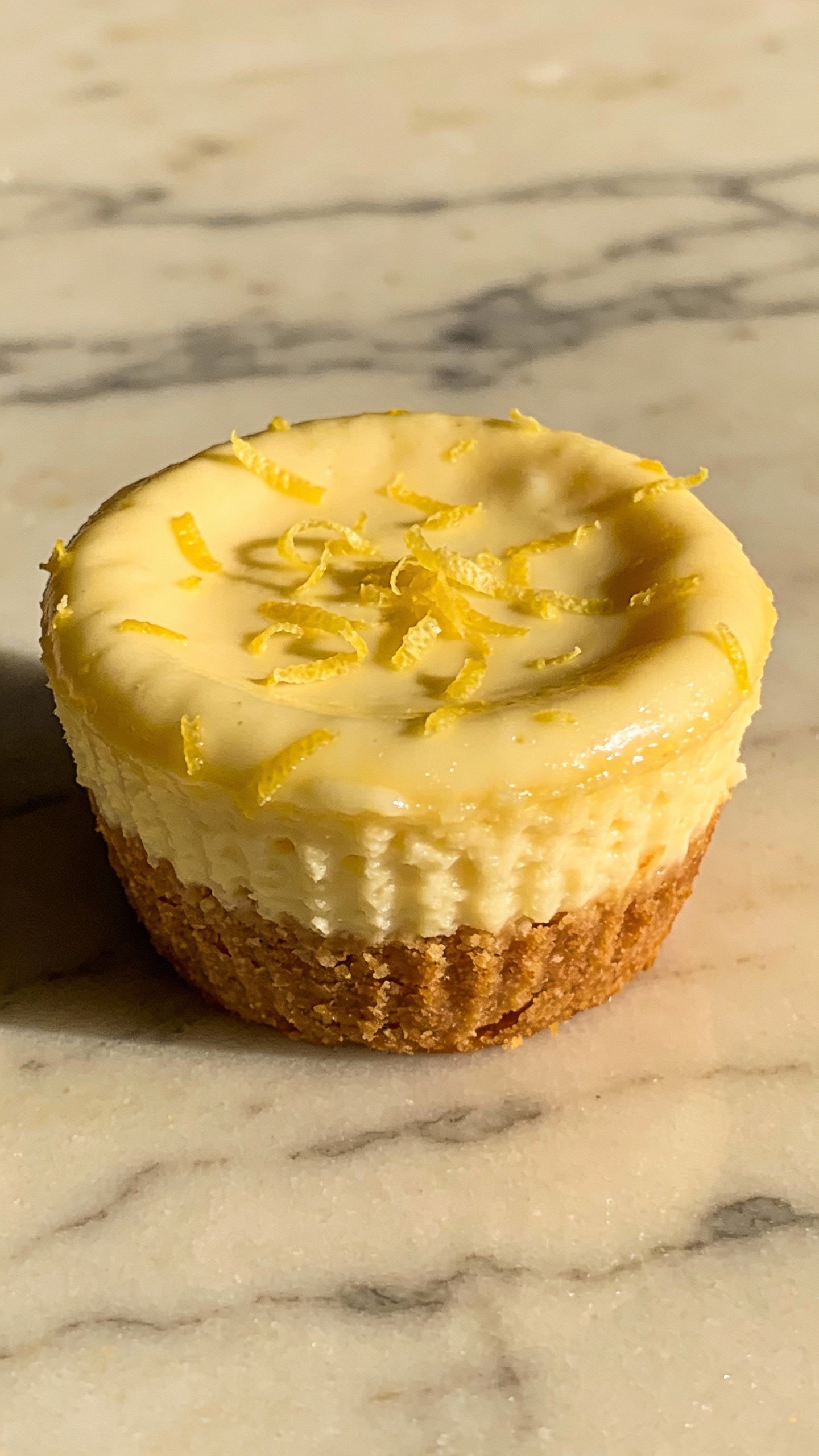 keto lemon cheesecake muffin topped with zest on marble