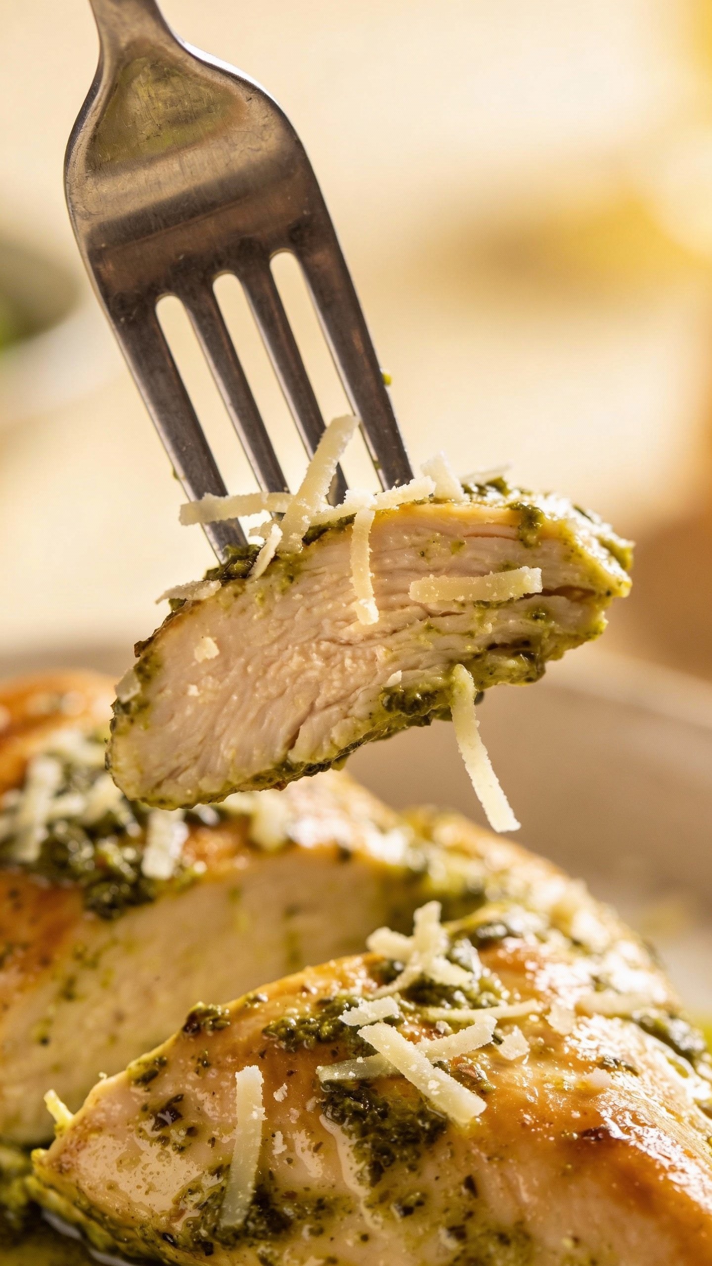 forkful of pesto-coated chicken breast with parmesan shavings