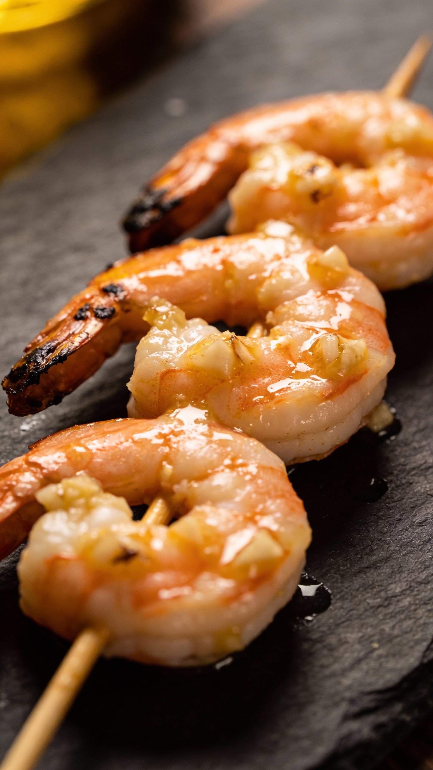 closeup garlic butter shrimp skewer on dark slate