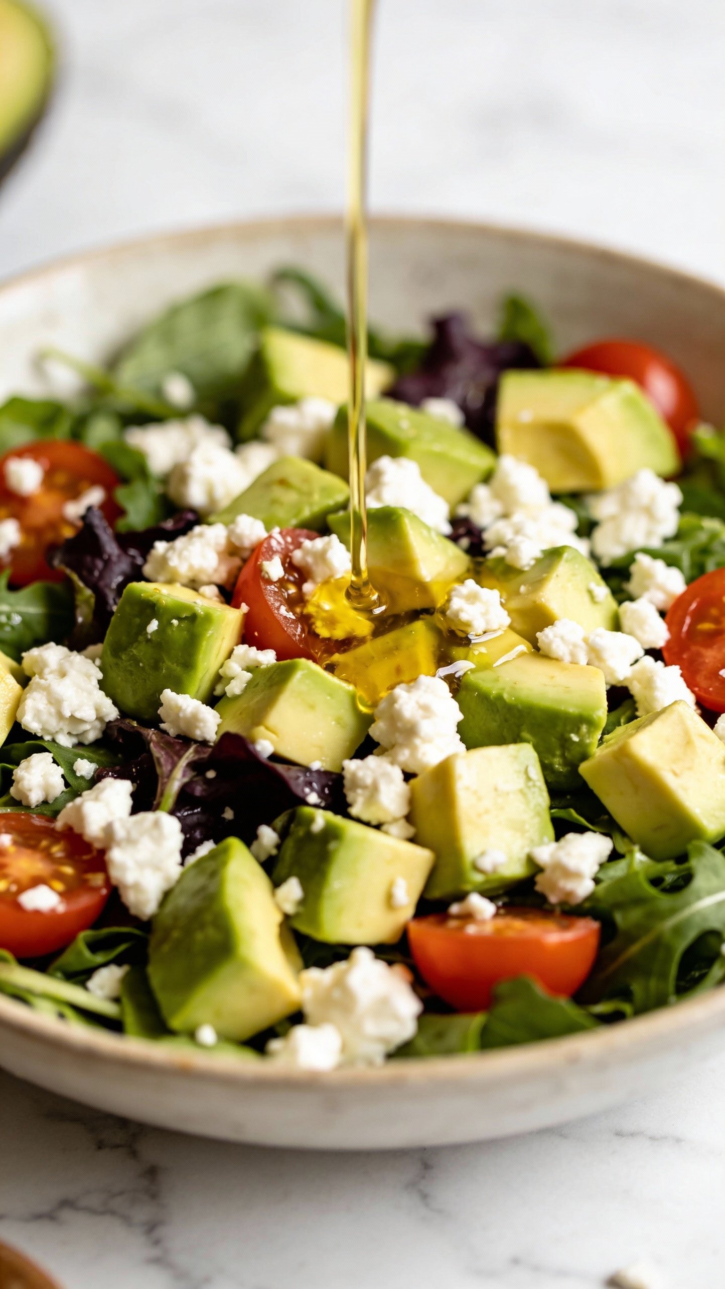 closeup bowl of avocado feta keto salad, white marble background