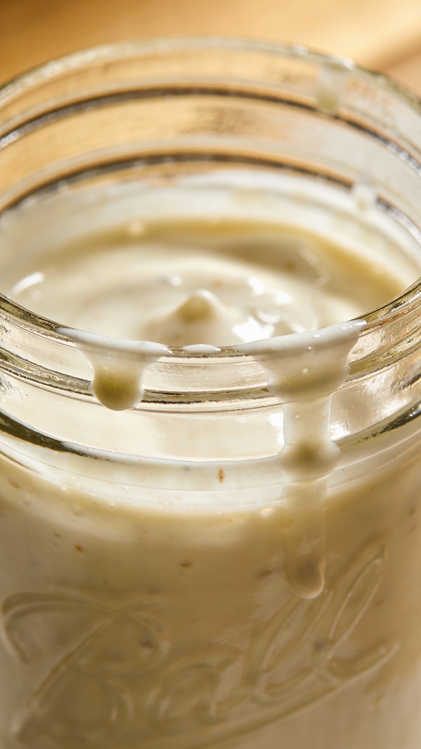 glass jar of creamy keto dressing, drips visible