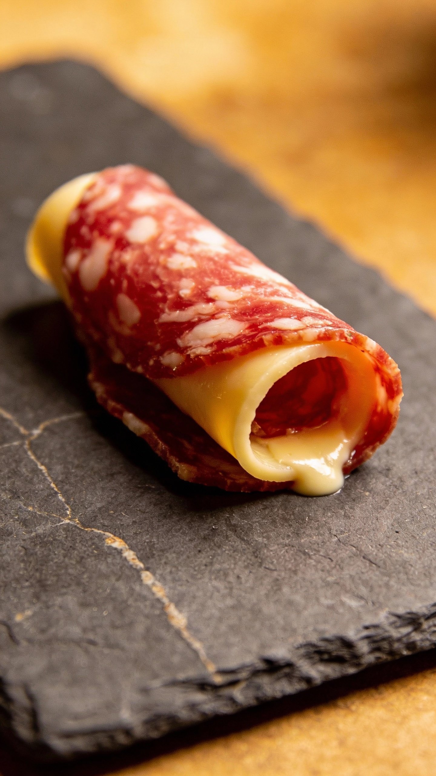single slice of salami and provolone roll-up on slate