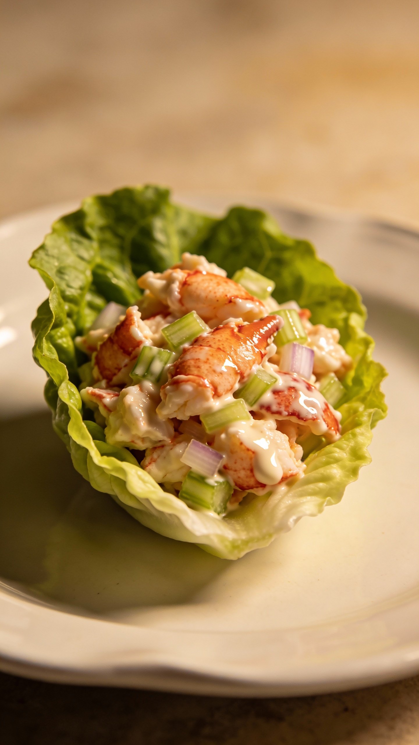 single lettuce cup filled with lobster salad, mayo glisten
