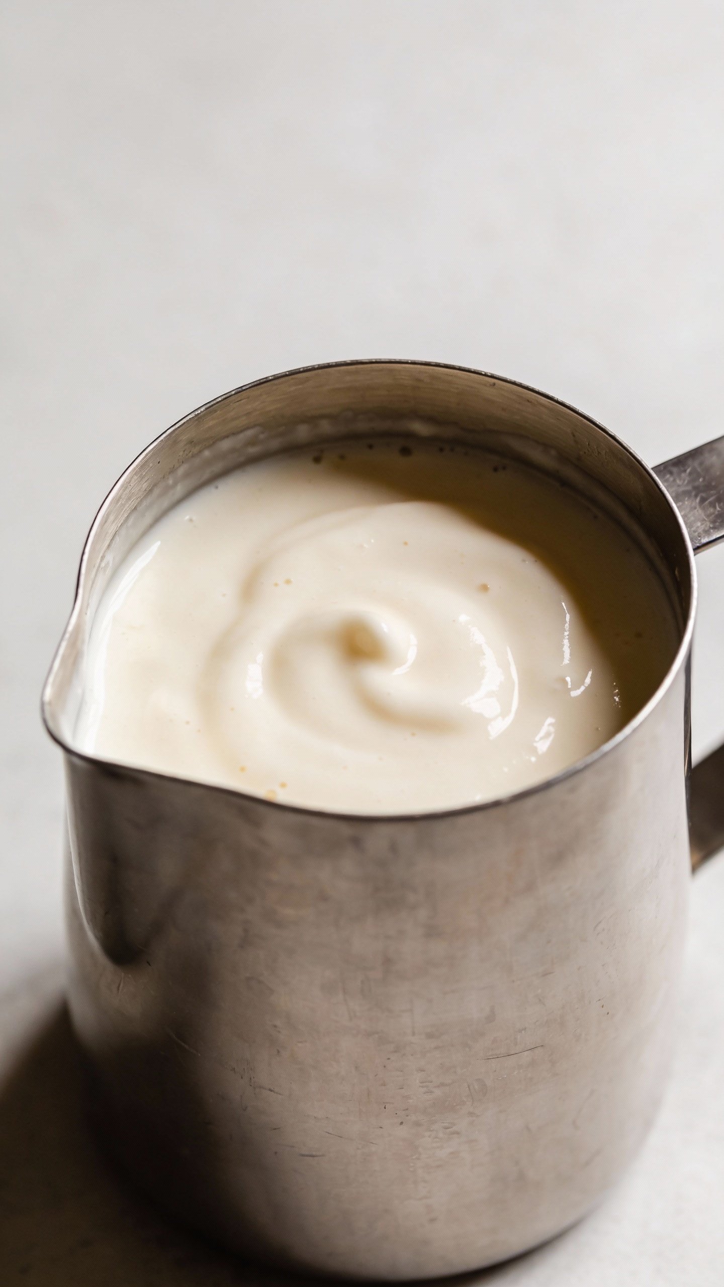 stainless blender jar filled with pale vanilla smoothie, top-down shot