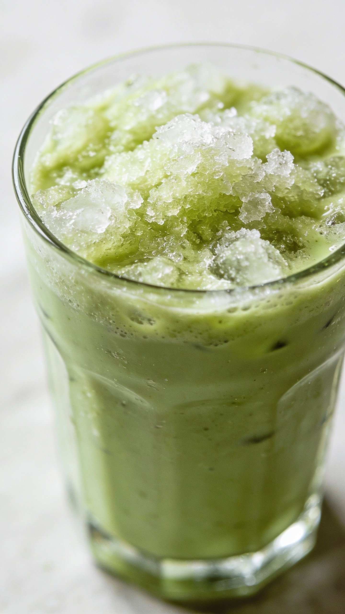 frosty matcha smoothie in clear glass, closeup, soft daylight