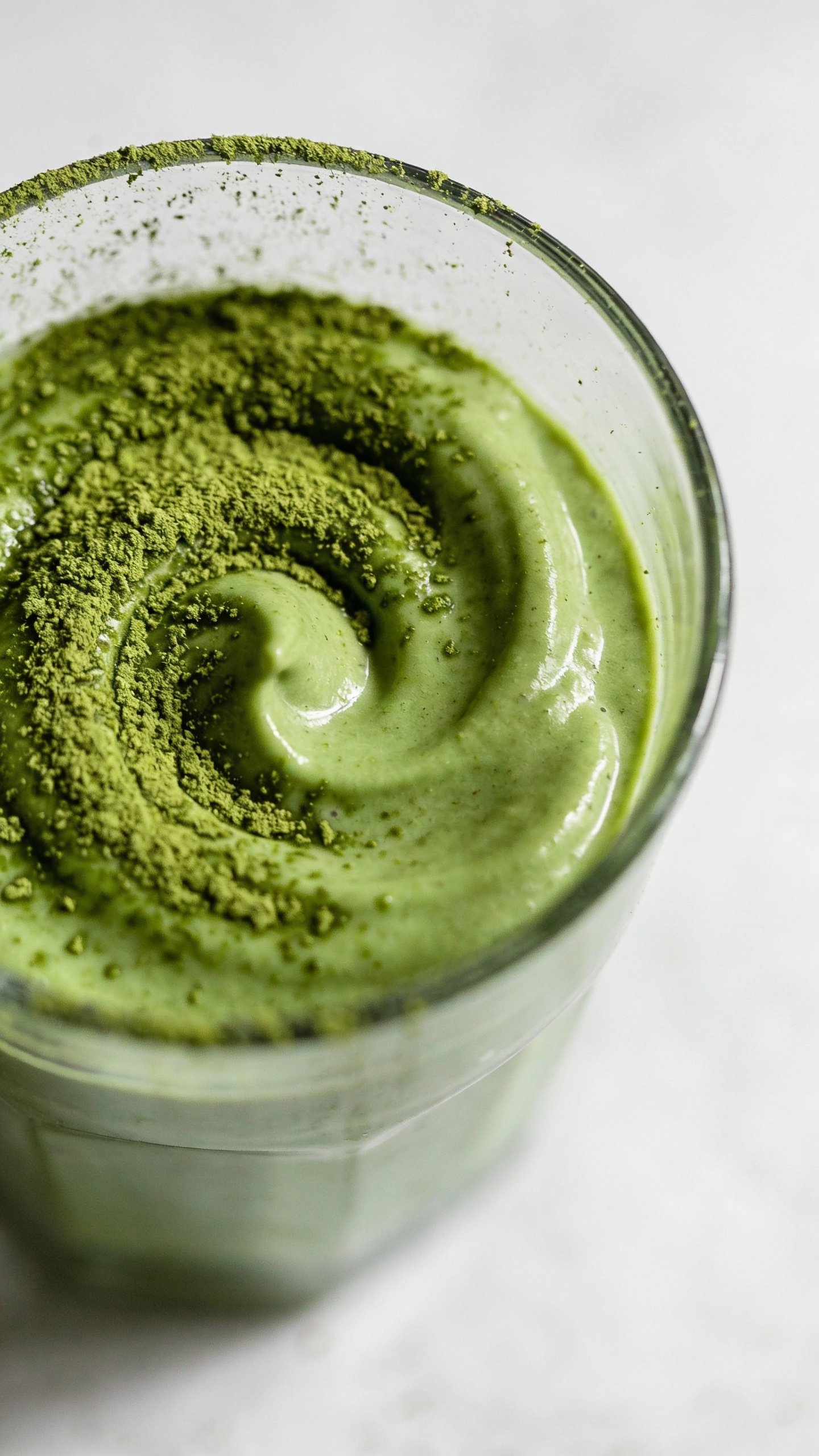 overhead shot of matcha-dusted smoothie swirl in glass