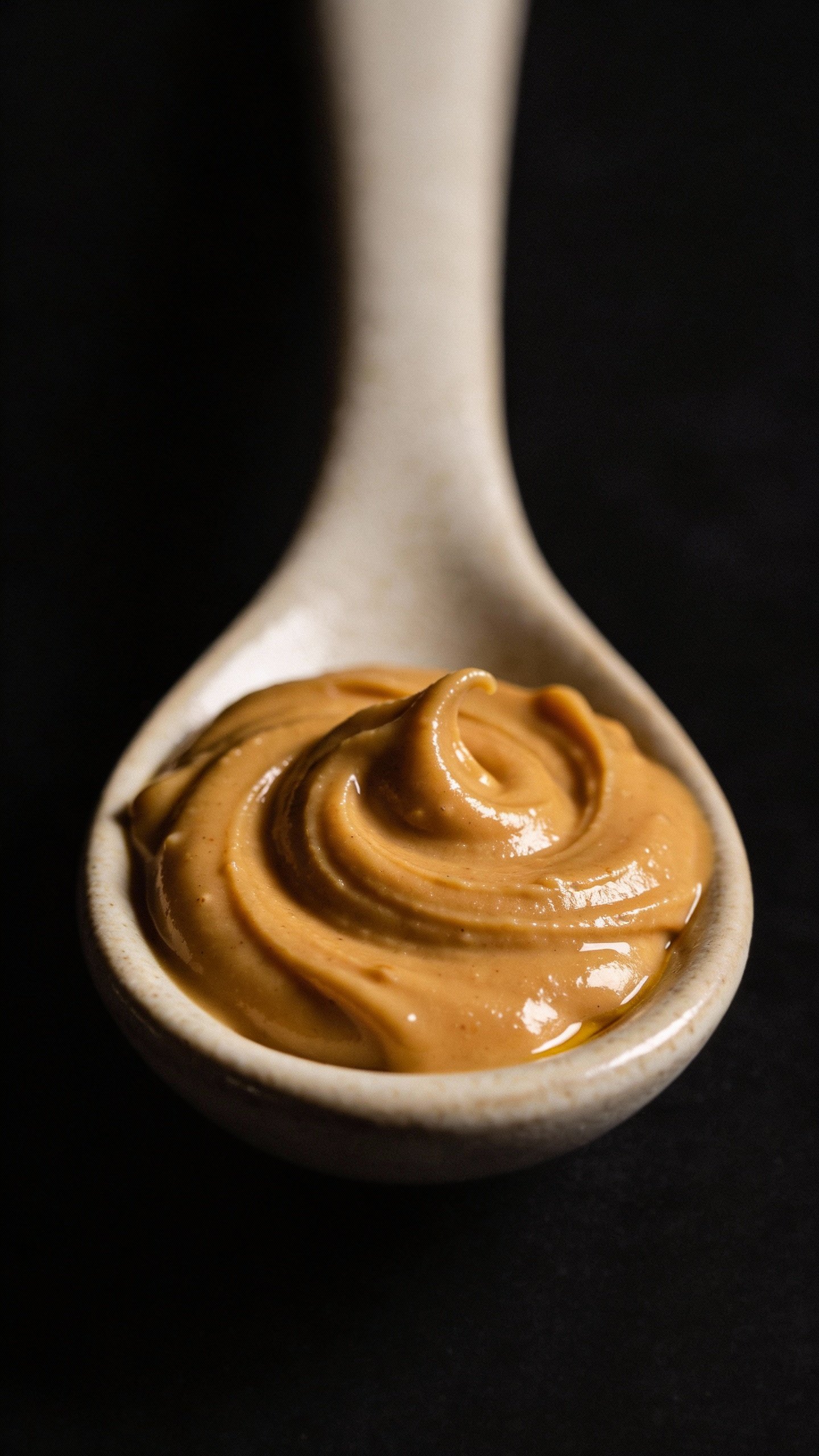swirl of peanut butter on ceramic spoon, studio lighting