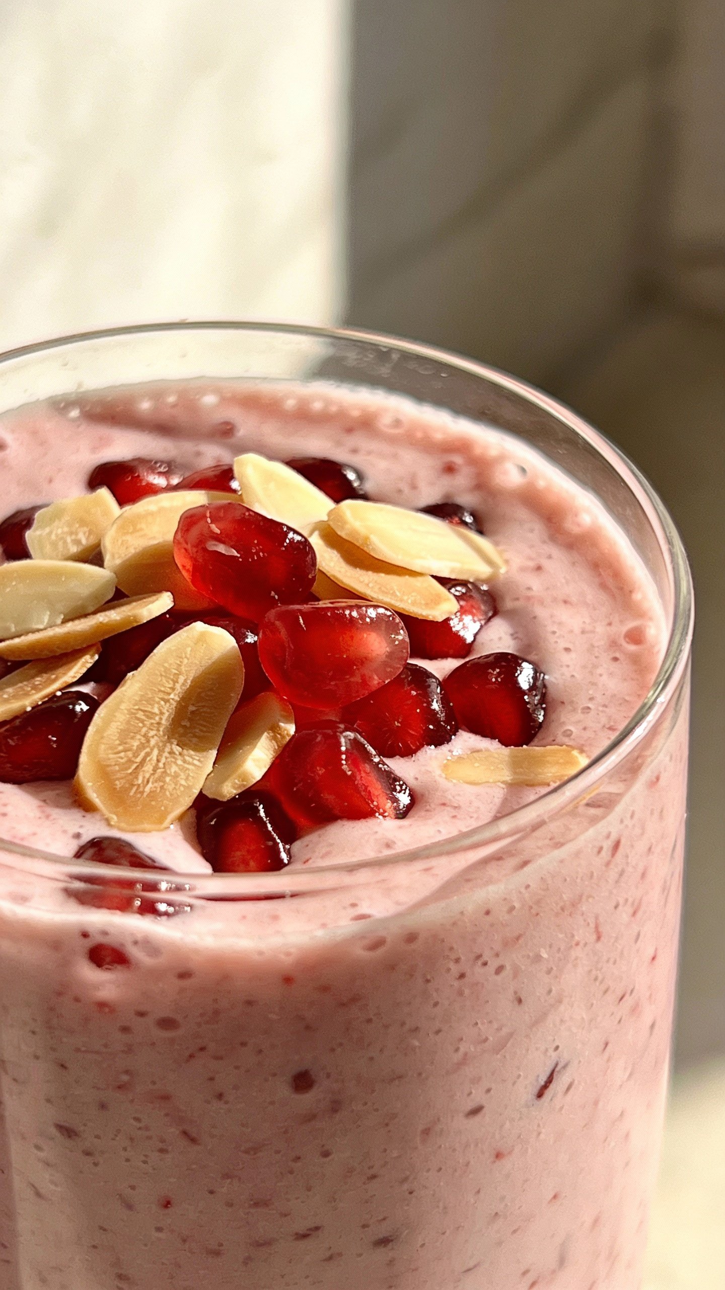 closeup cherry almond smoothie in clear glass, soft window light