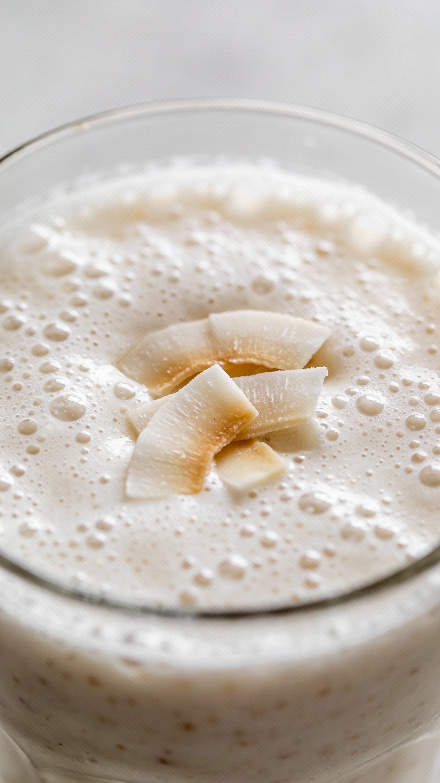 frosty vanilla coconut protein smoothie in clear glass, closeup