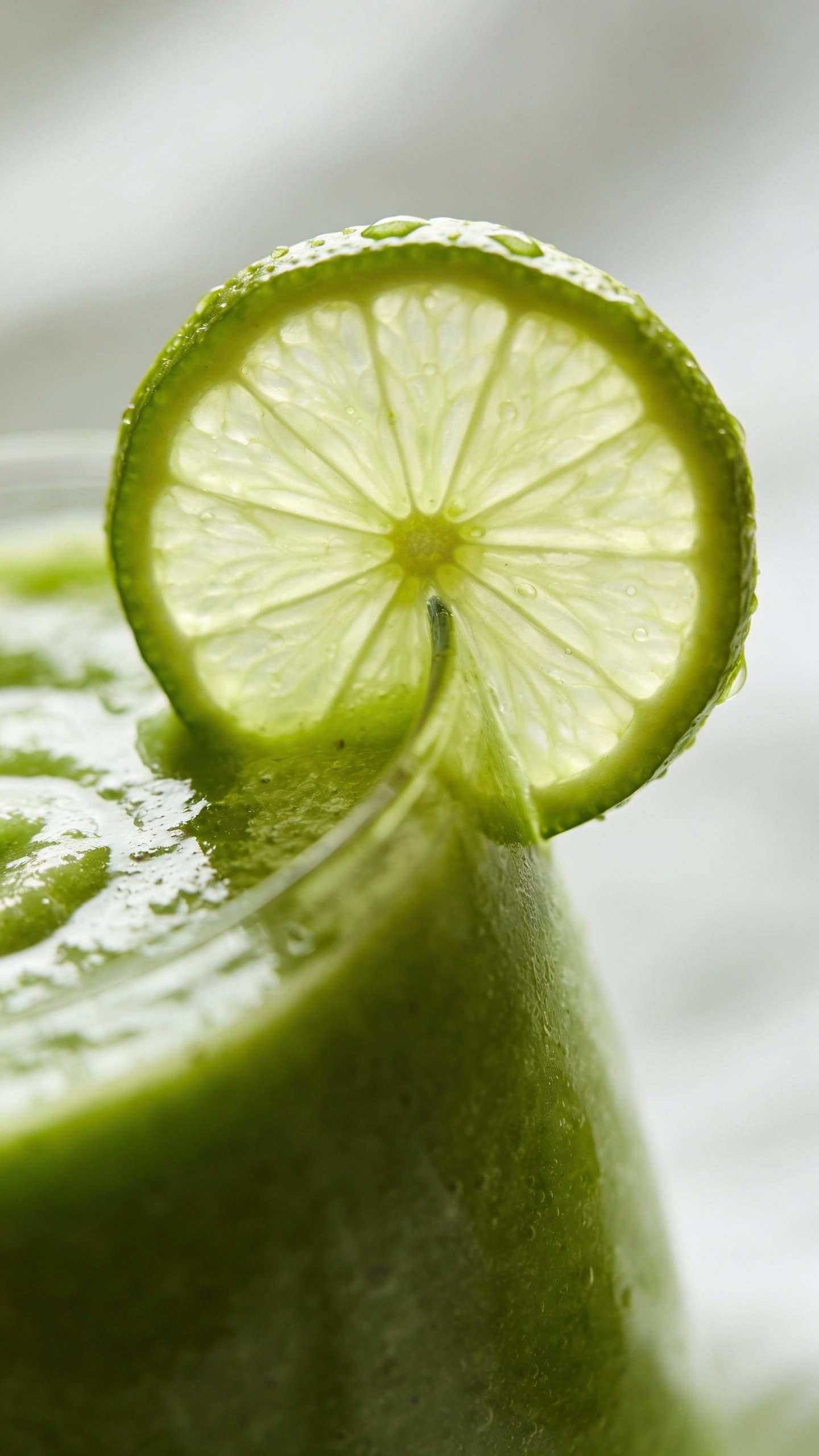 Single lime wheel perched on smoothie rim, macro shot