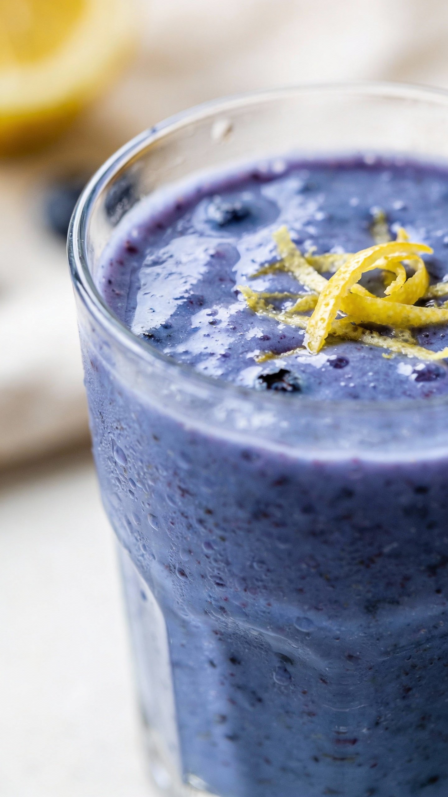 closeup blueberry lemon zest smoothie in clear glass, soft daylight