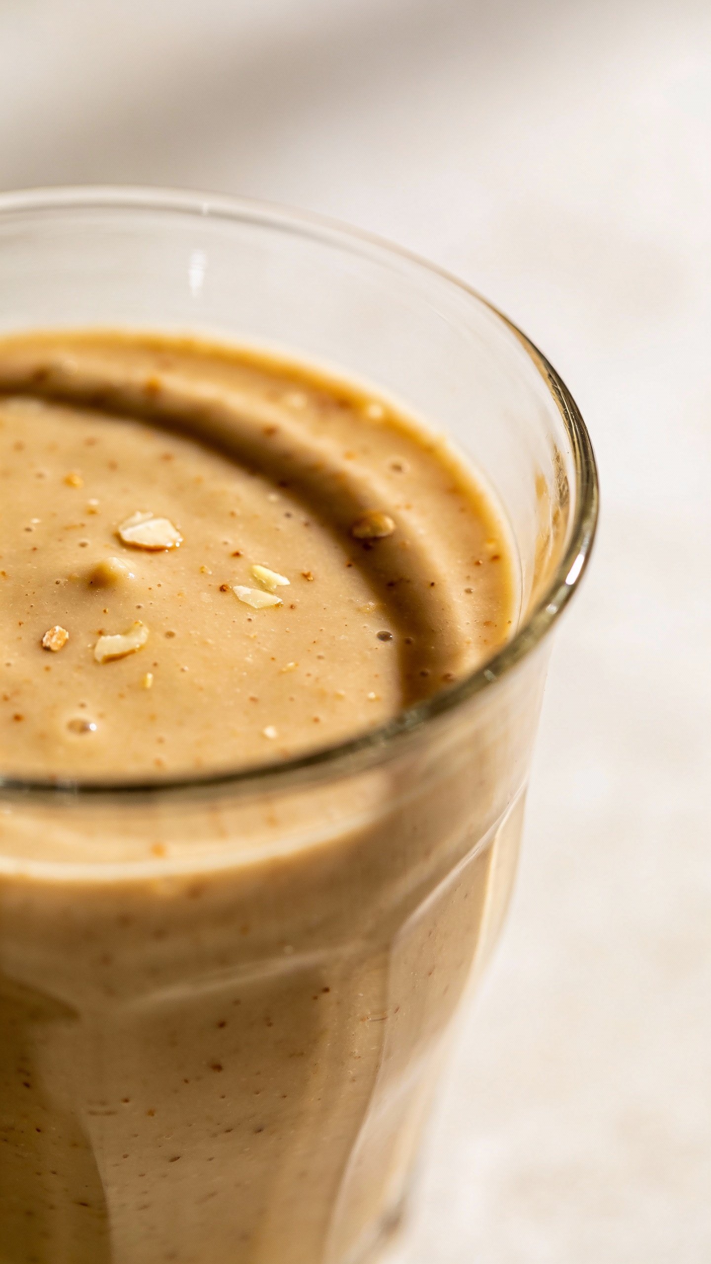 closeup vanilla almond butter smoothie in clear glass, soft light
