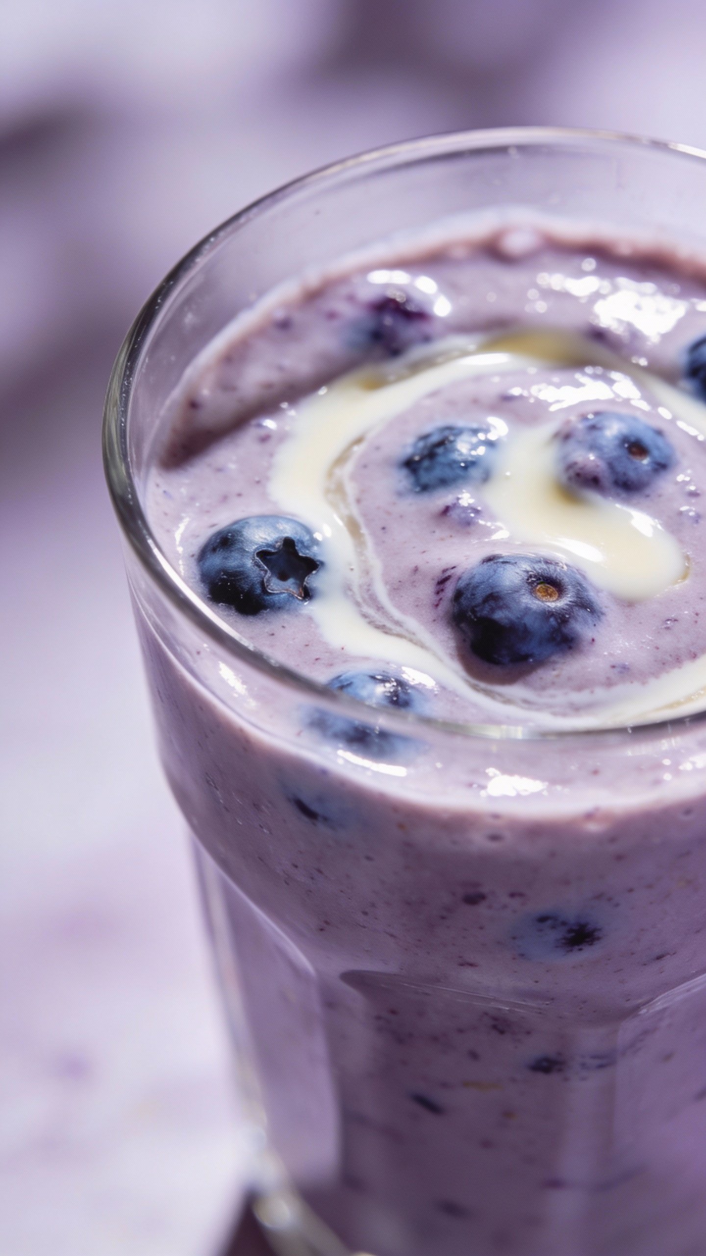 closeup blueberry vanilla smoothie in clear glass, soft purple