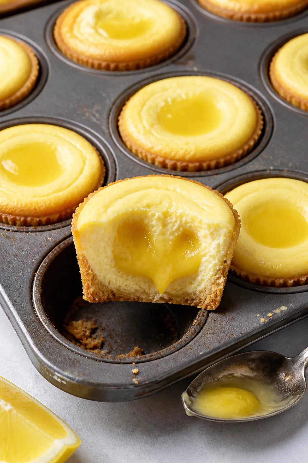 Close-up detail and process: Mini lemon curd–stuffed cheesecake bites just out of the oven in a si