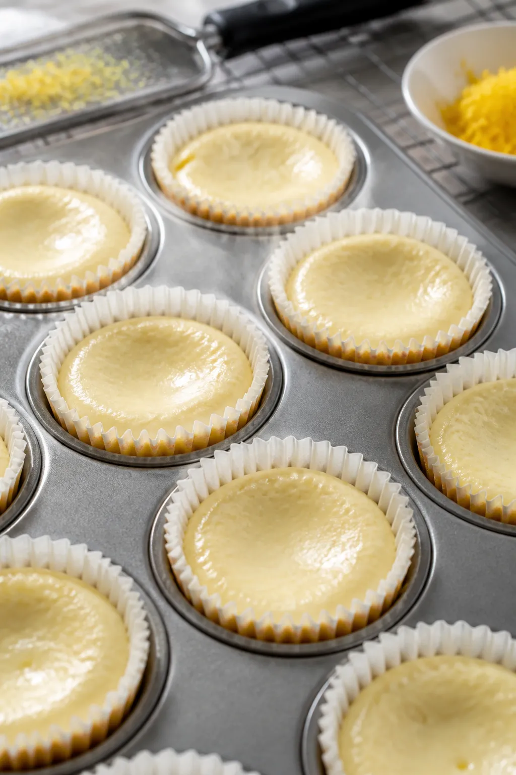 Close-up detail and process: Mini low carb lemon cheesecake cupcakes just out of the oven, set edges