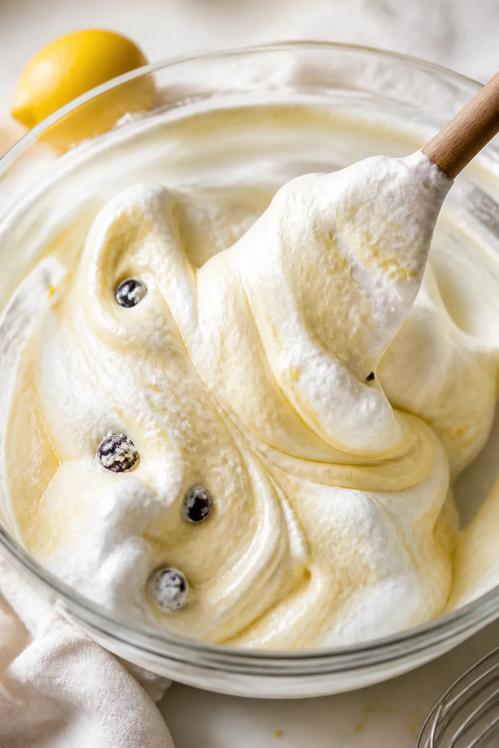 Close-up detail, cooking process: A glossy ribbon of pale golden batter being gently folded with sno
