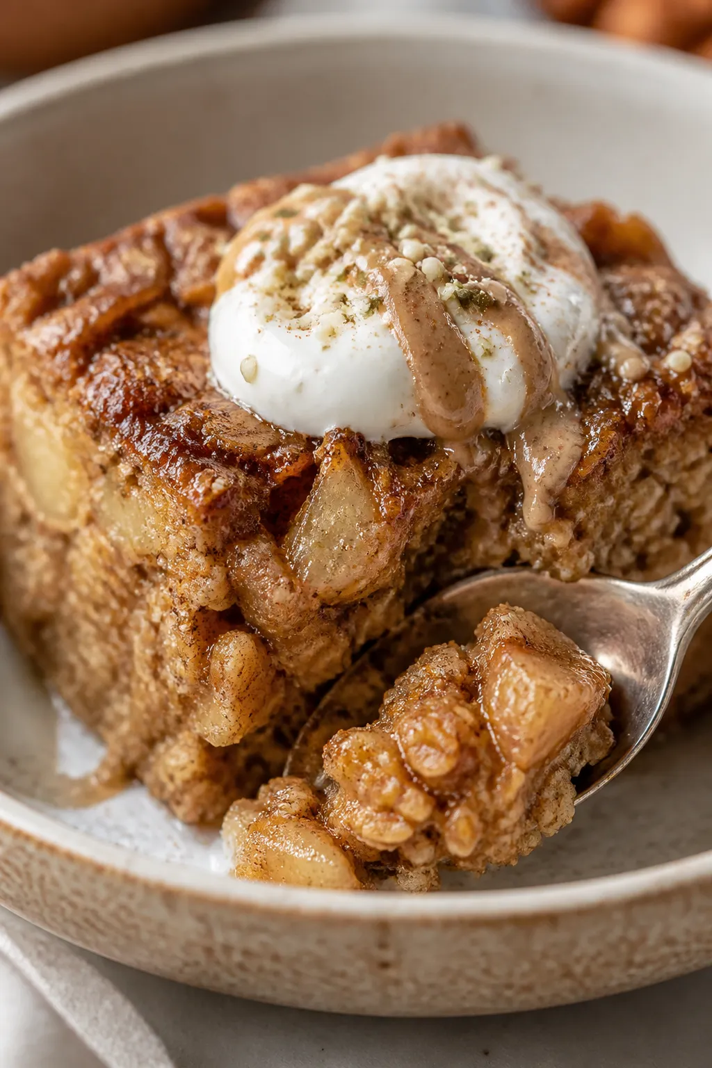 Close-up detail of a plated square of the Cinnamon Apple Bake in a shallow ceramic bowl, texture-for
