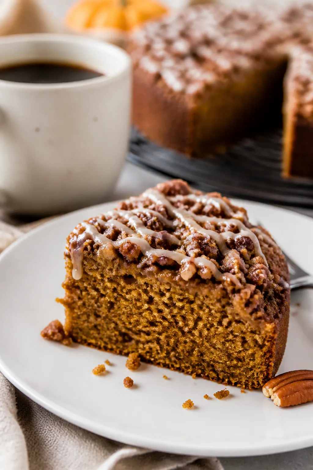 Close-up detail of a sliced piece of pumpkin crumb cake on a matte white dessert plate, tender pumpk