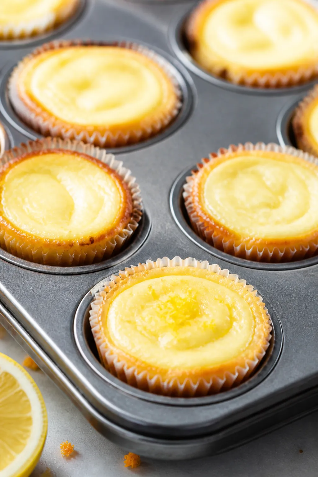 Close-up detail shot: A tray of freshly baked low-carb lemon cheesecake bites in a mini muffin tin, 