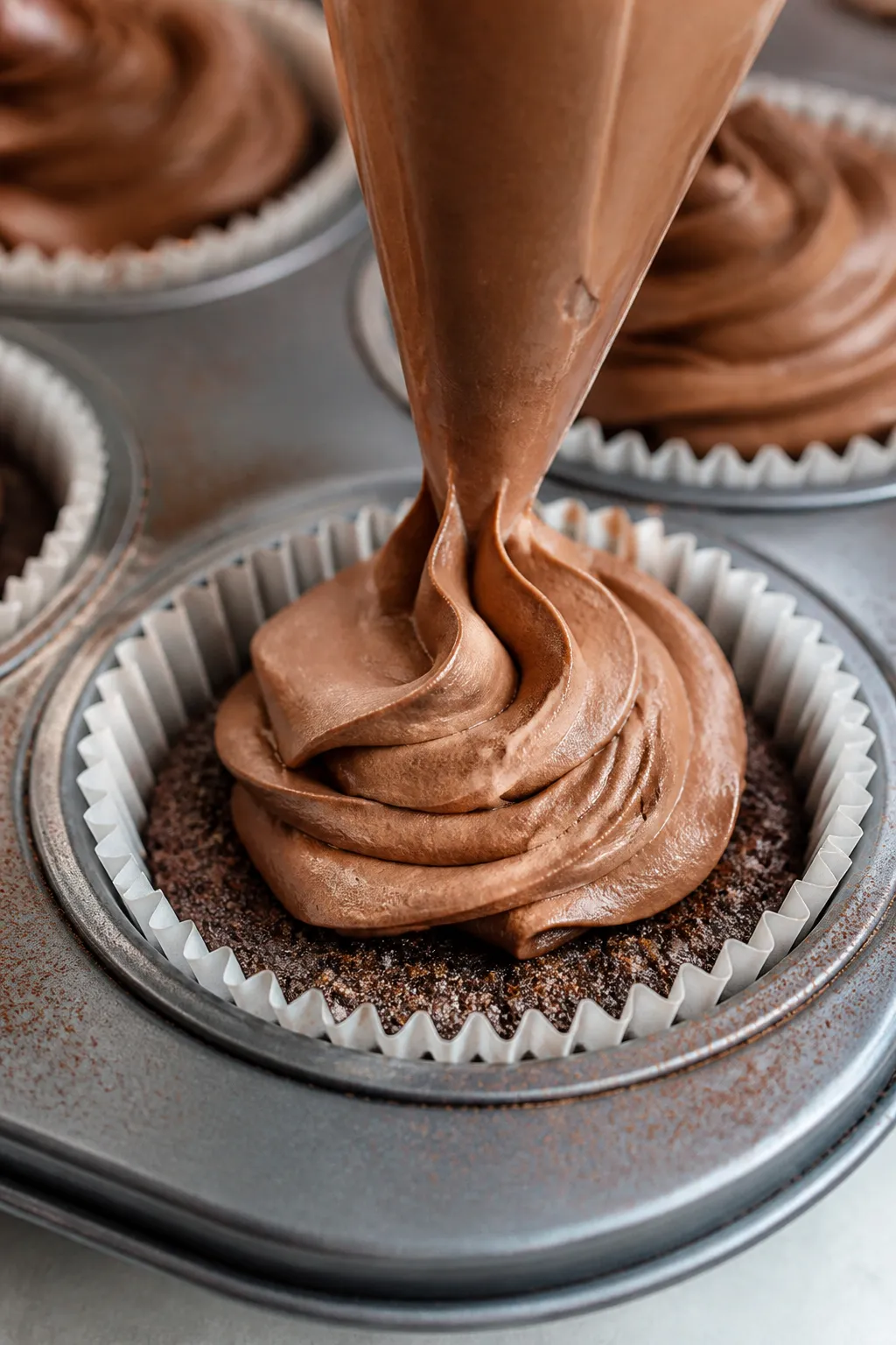 Close-up detail shot of a no-bake chocolate cheesecake cup being filled: a piping bag swirling thick