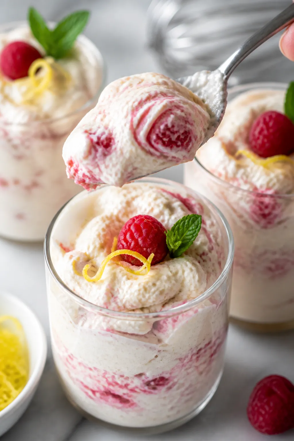 Close-up detail shot of the finished Low Carb Lemon Raspberry Mousse being spooned into clear desser