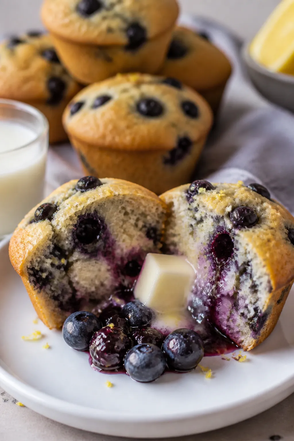 Close-up plated presentation of a split-open Low Carb Blueberry Protein Muffin on a matte white plat