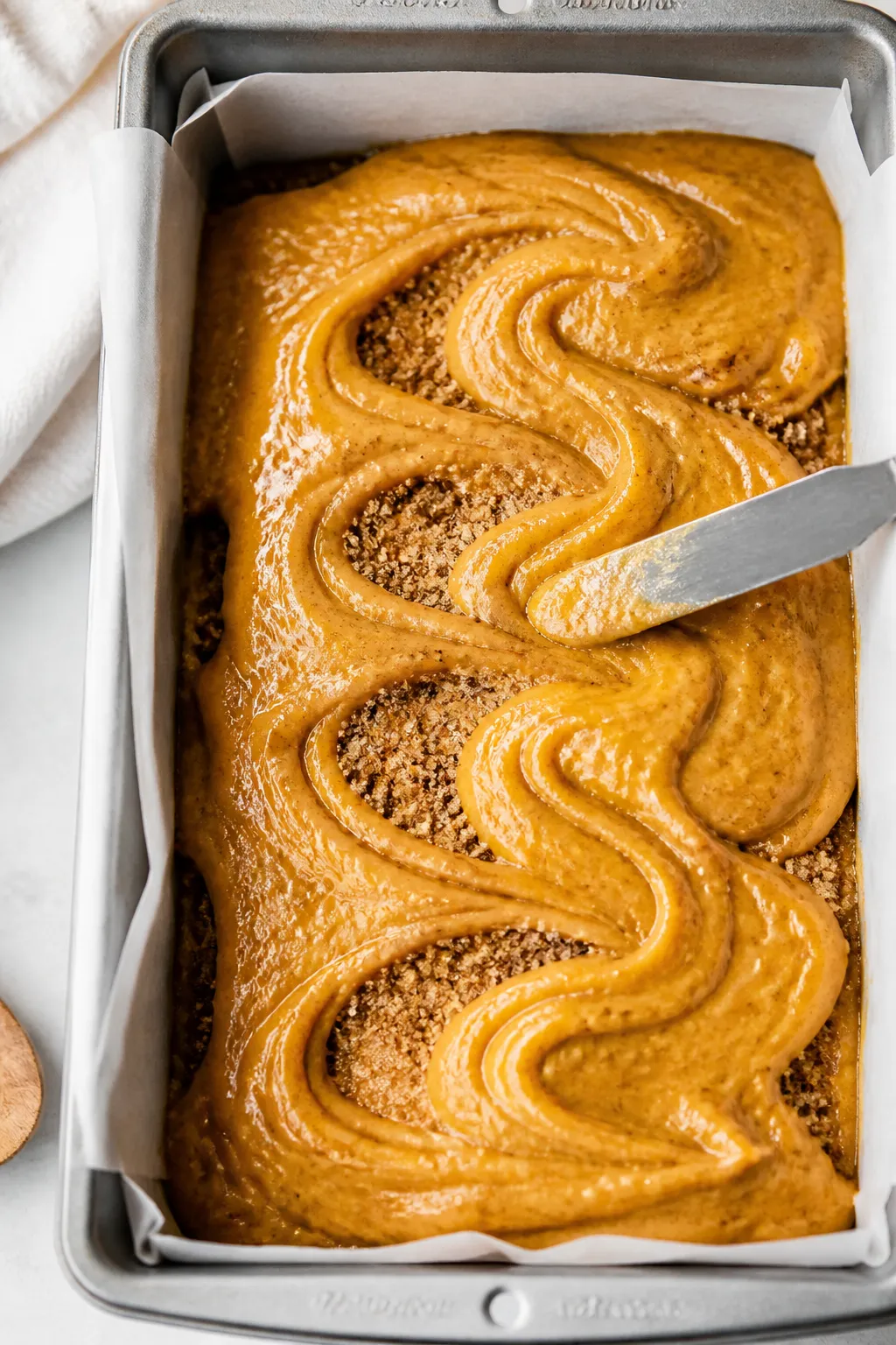 Close-up process shot of the layering and gentle S-shaped swirling: a 9x5 parchment-lined loaf pan f