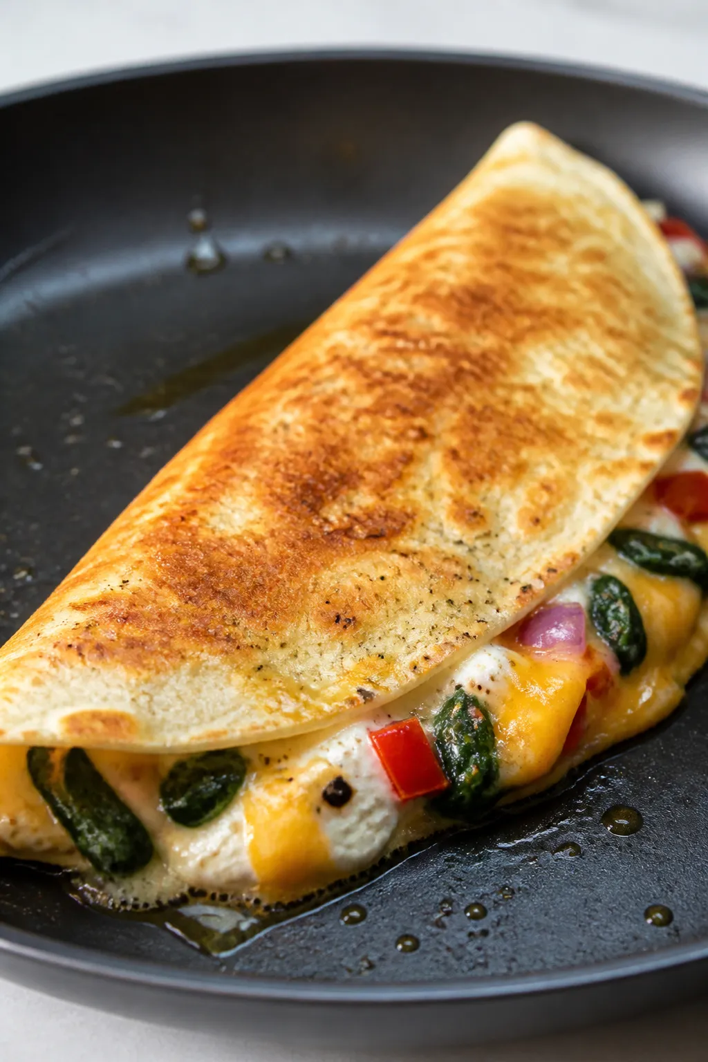 Cooking process close-up: Half-moon egg white breakfast quesadilla sizzling in a nonstick skillet, t