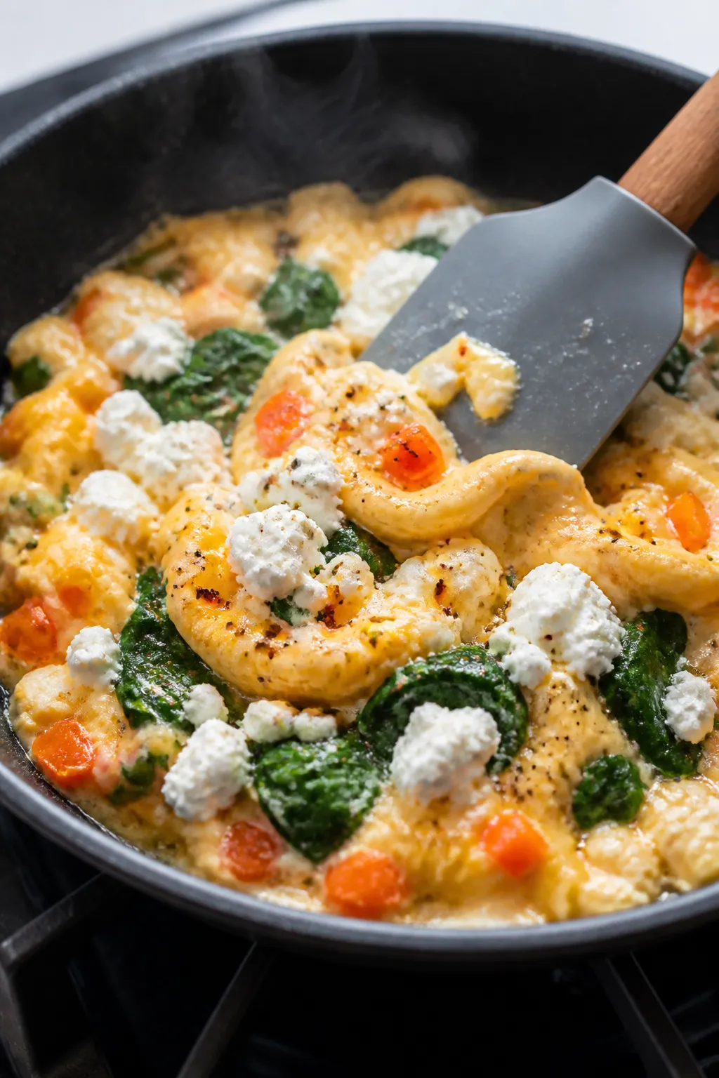 Cooking process close-up: Soft-scramble eggs halfway set in a small nonstick skillet over medium hea