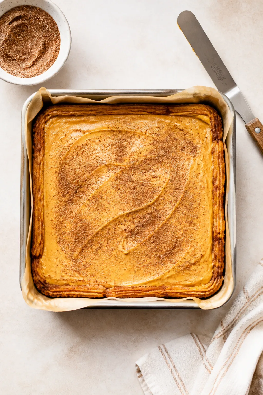 Overhead cooking-process shot of the batter stage: the par-baked golden churro crust set in an 8×8-