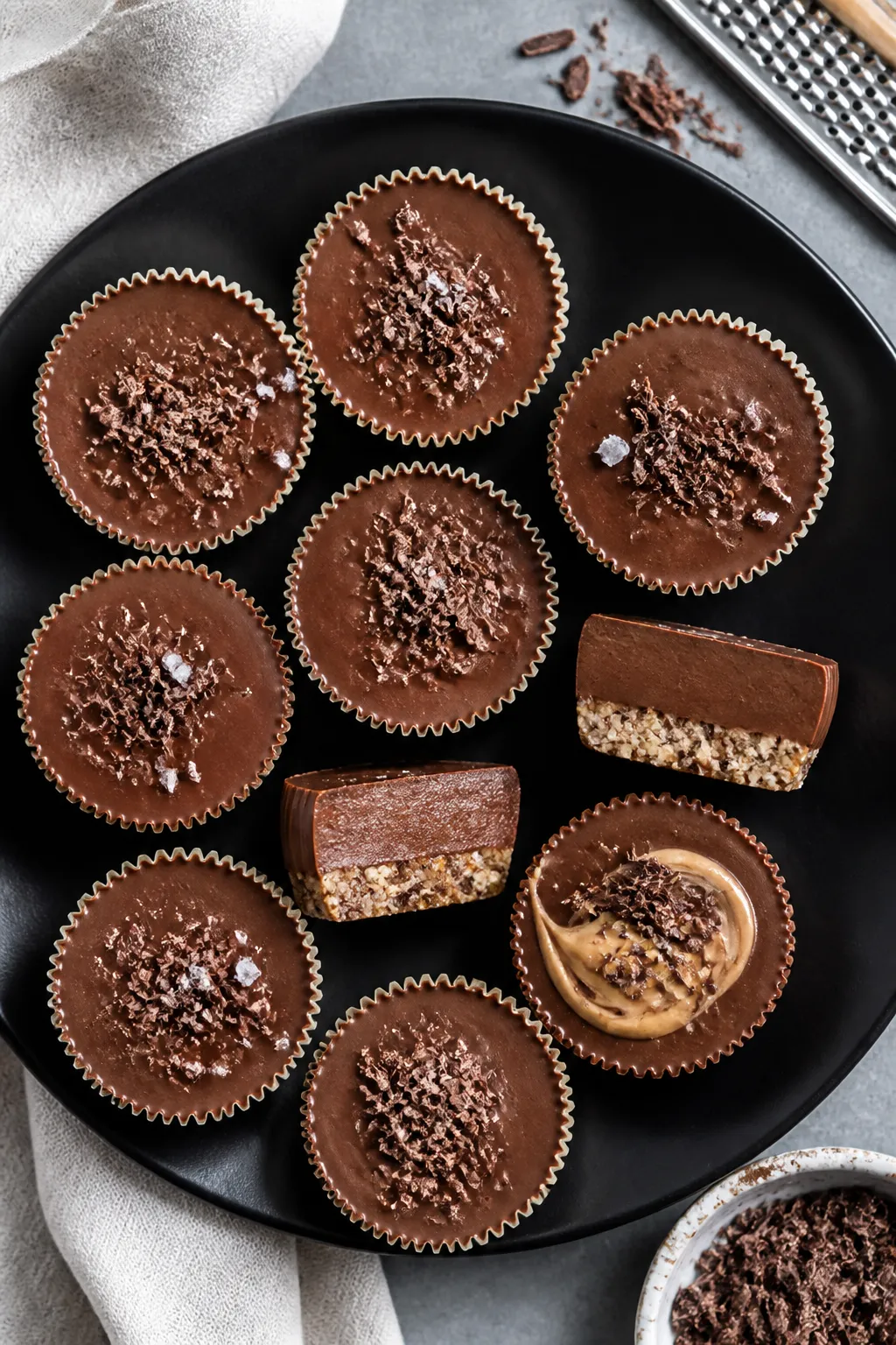 Overhead final presentation of set no-bake chocolate cheesecake cups on a matte black plate: smooth,