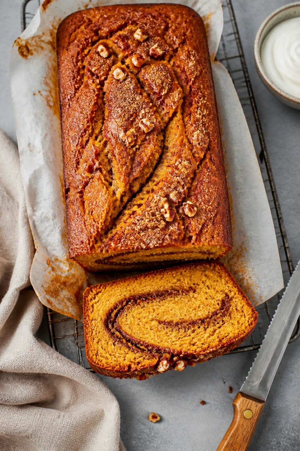 Overhead shot of a freshly baked Keto Pumpkin Cinnamon Swirl Cake loaf on a wire rack, parchment ove