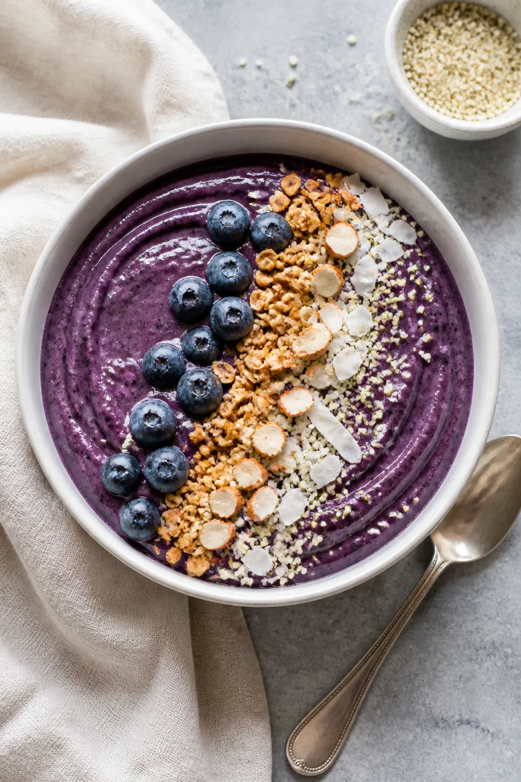 Overhead shot of a freshly blended High Protein Blueberry Smoothie Bowl poured into a chilled matte-