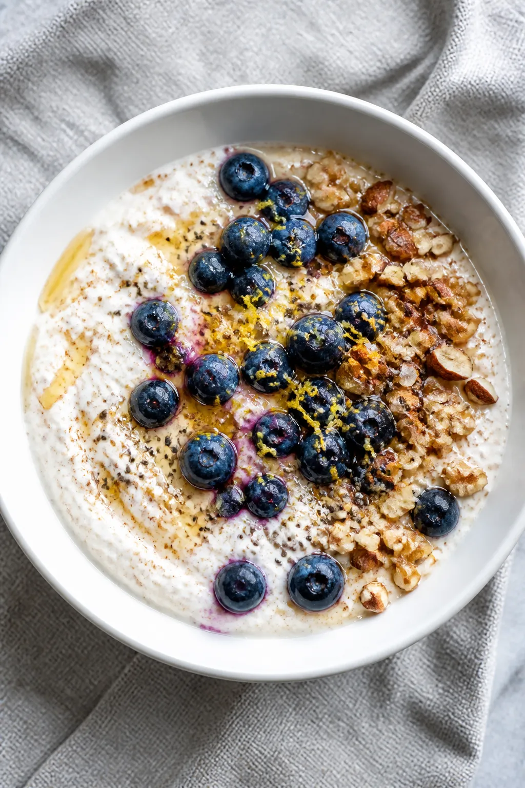 Overhead shot of a prepared Cottage Cheese Blueberry Breakfast Bowl mid-assembly: silky cottage chee