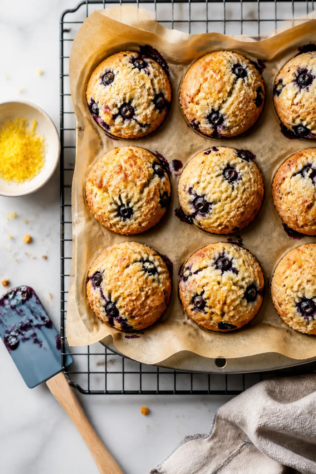 Overhead shot of freshly baked Low Carb Blueberry Protein Muffins cooling in a parchment-lined muffi