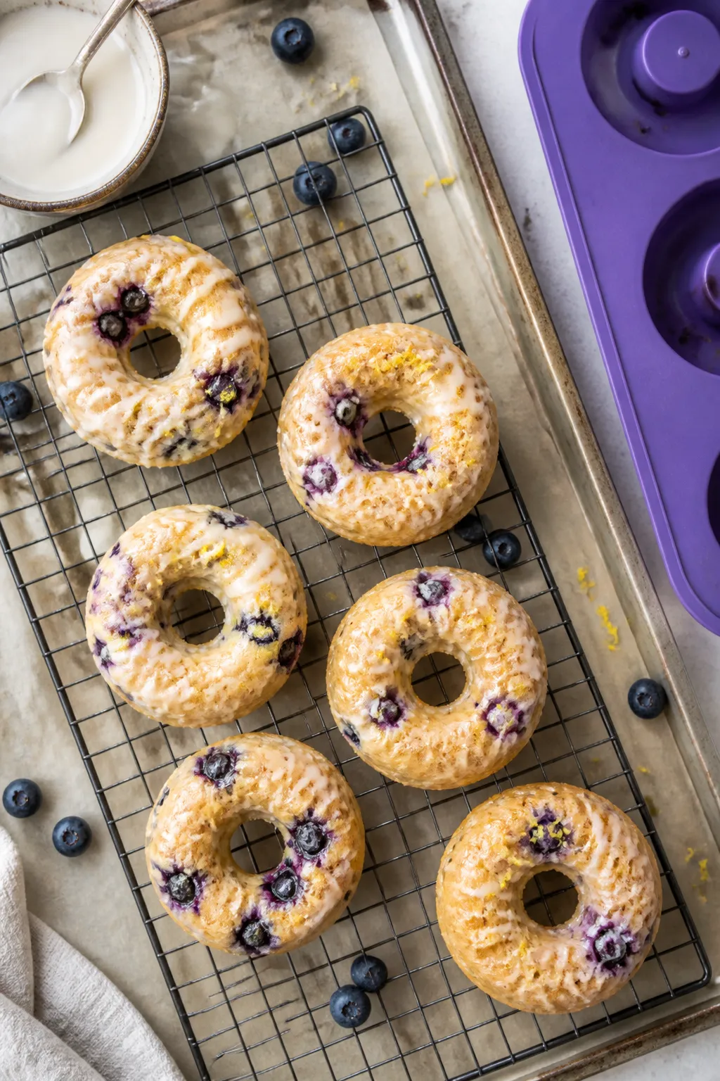 Overhead shot of freshly baked low carb blueberry protein donuts cooling on a wire rack, golden cake