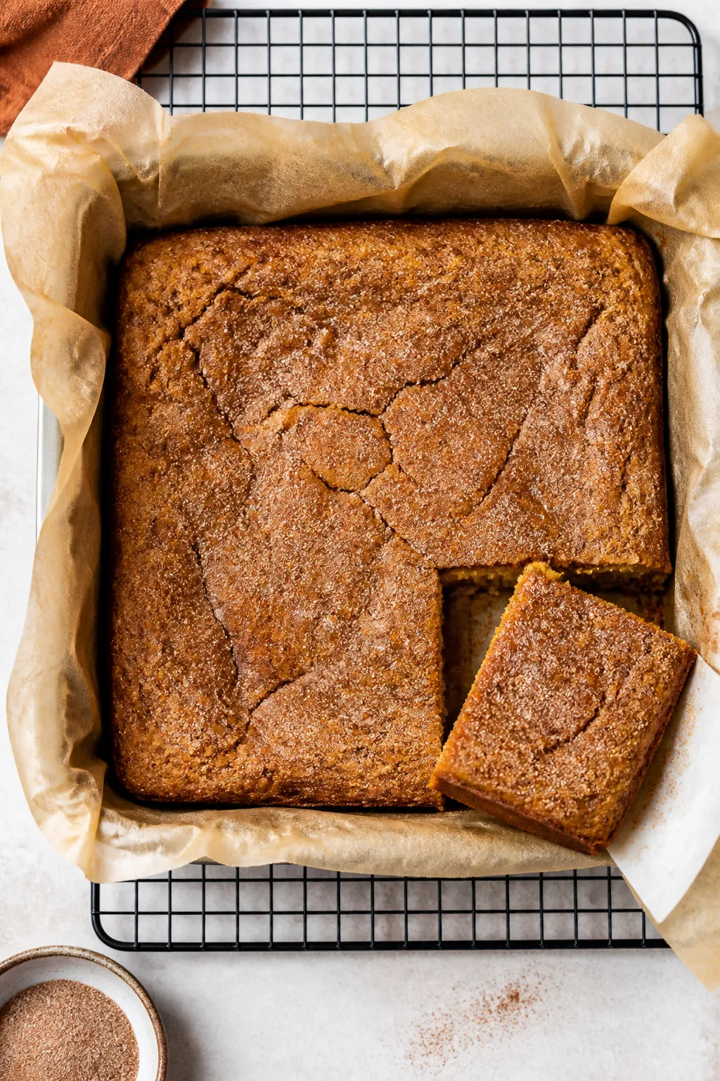 Overhead shot of freshly baked Low Carb Pumpkin Snickerdoodle Bars cooling in a parchment-lined 8x8 