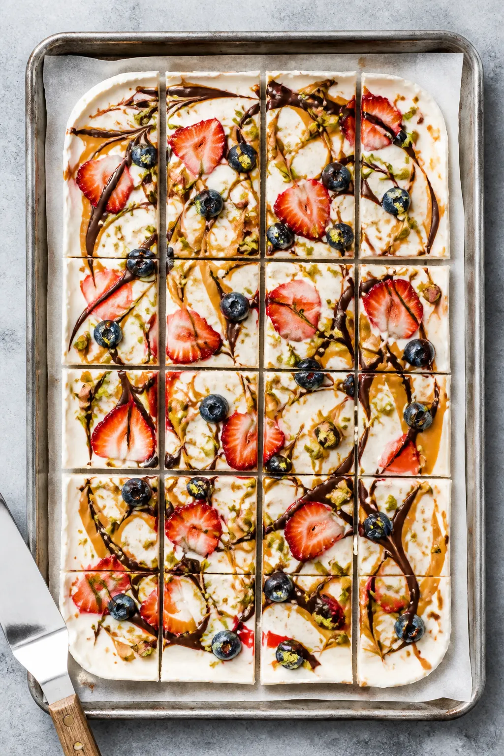 Overhead shot of freshly frozen Greek Yogurt Protein Bark slab on a parchment-lined baking sheet, sc