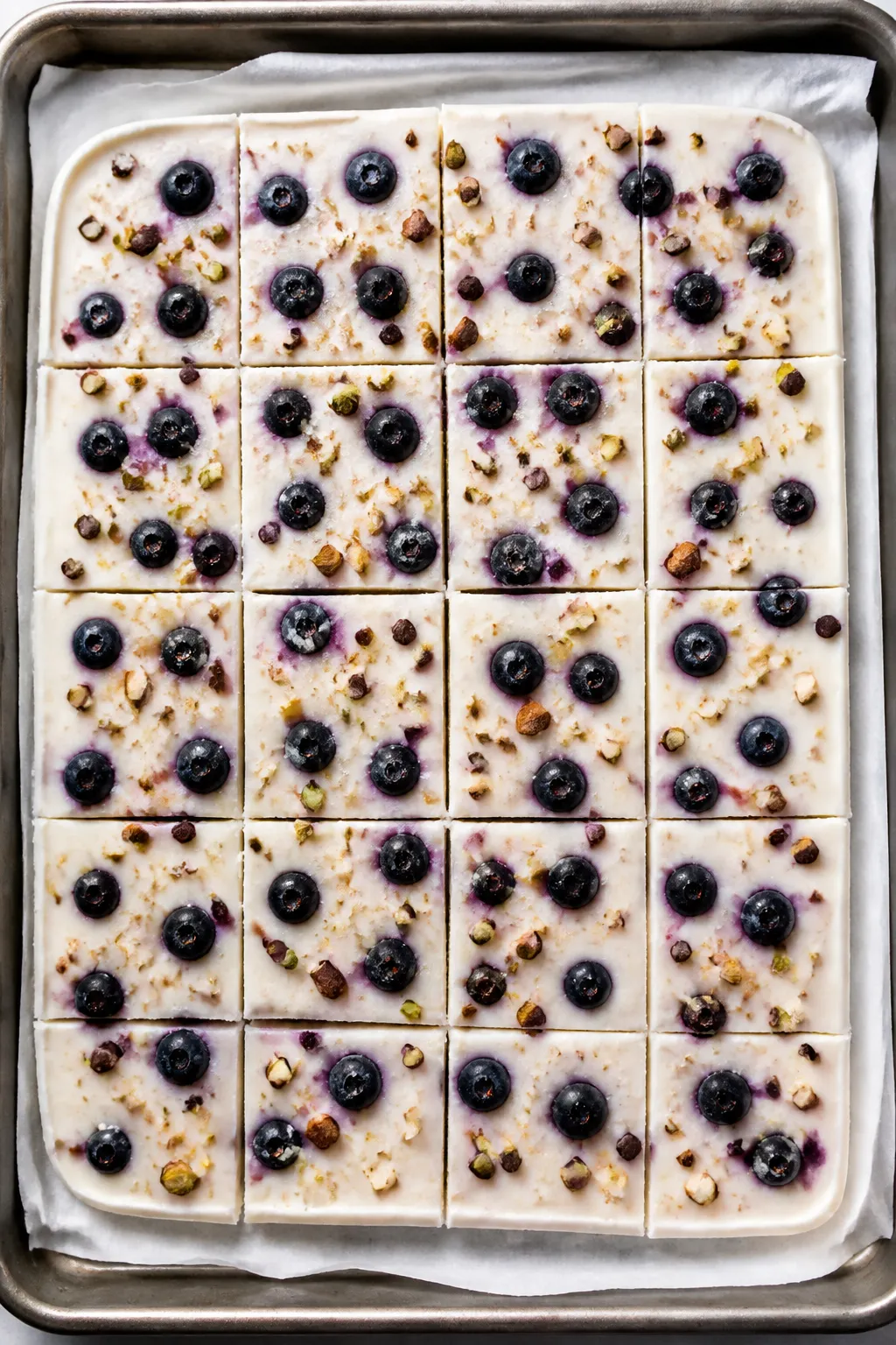 Overhead shot of freshly frozen High Protein Blueberry Greek Yogurt Bark on a parchment-lined baking
