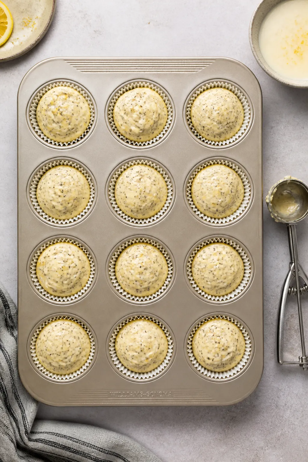 Tasty top view process shot: overhead of a 12-cup muffin tin lined with papers, batter evenly scoope